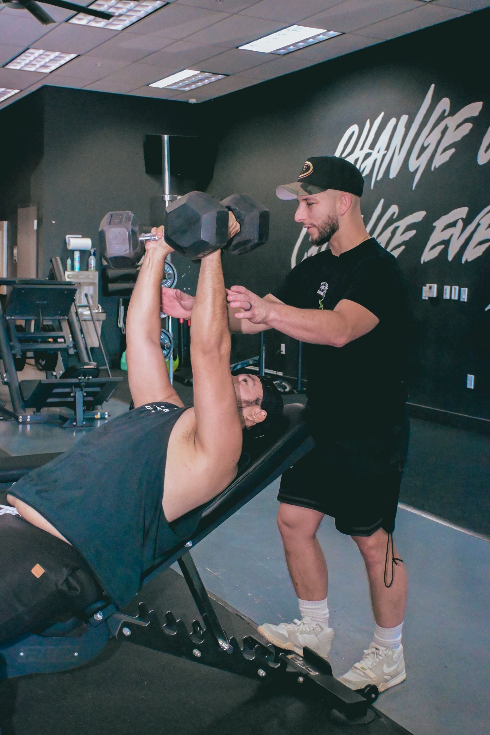 A personal trainer guides a client during a dumbbell workout